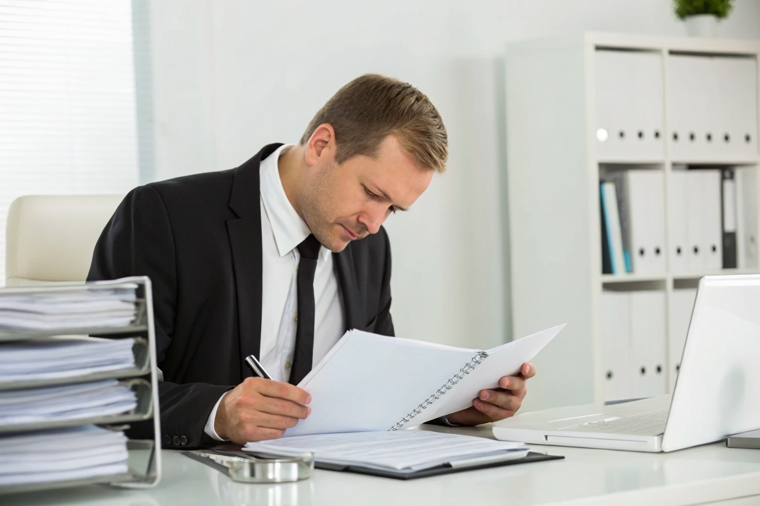 Auditor examining payroll records and contracts for workers comp liabilities.