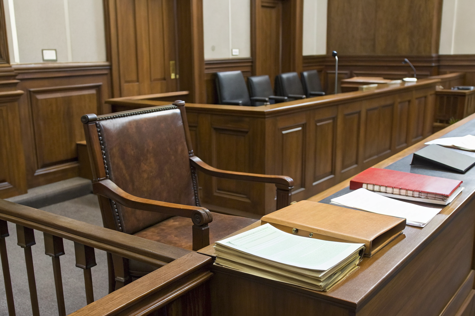 Empty courtroom bench with legal documents in foreground.
