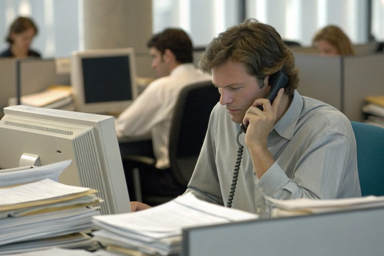 Surplus lines broker at desk with insurance papers and computer in office.